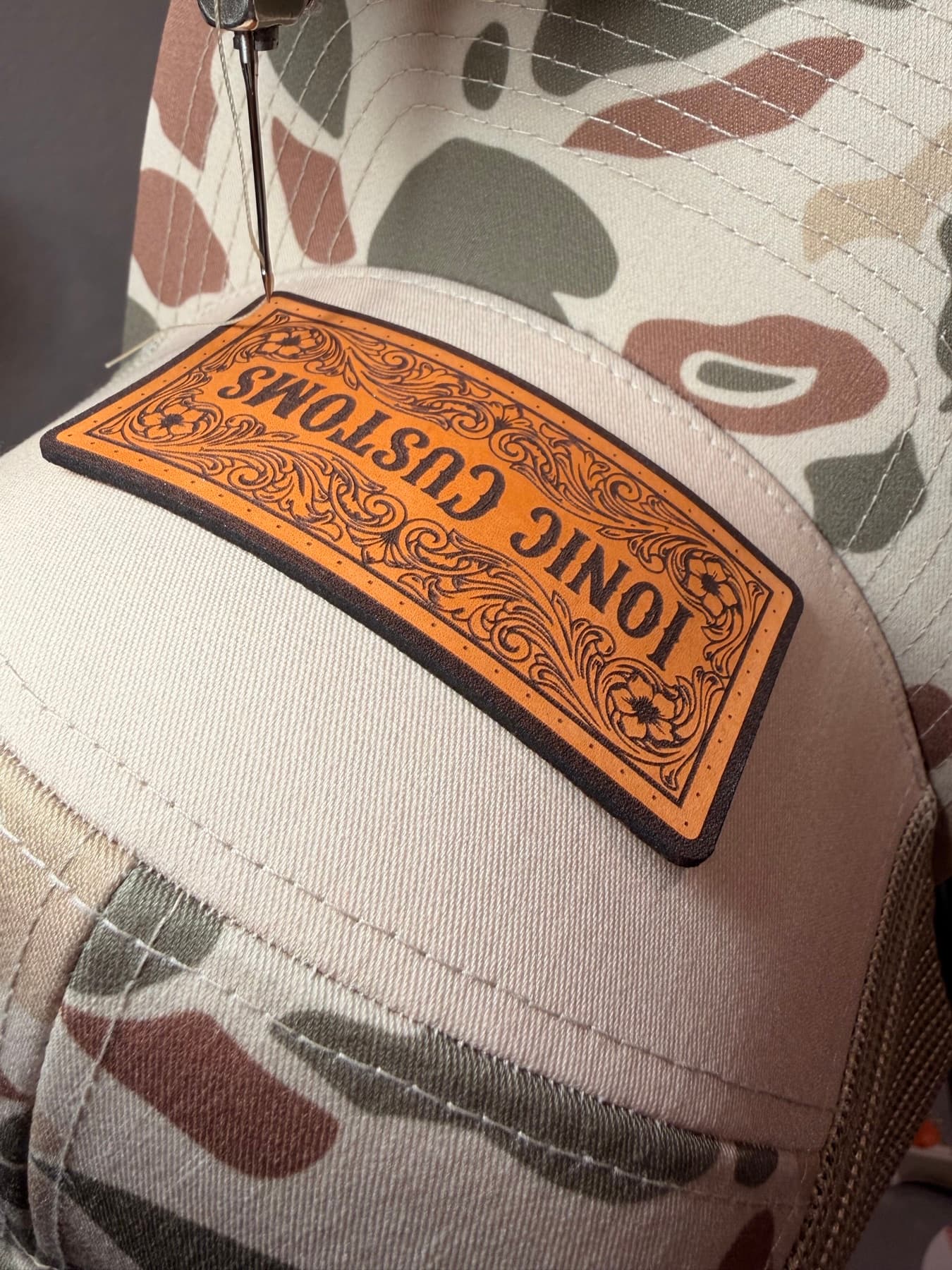 Duck camo trucker hat with a western floral-tooled leather patch
